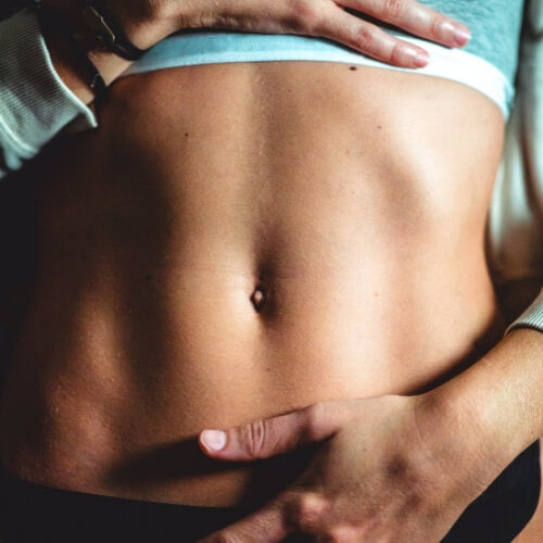 Woman holding stomach feeling bloated post meal. 
