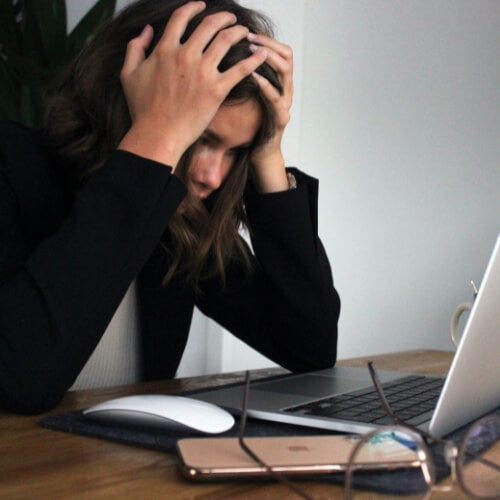Woman sitting at the desk experiencing stress and anxiety as she works. 