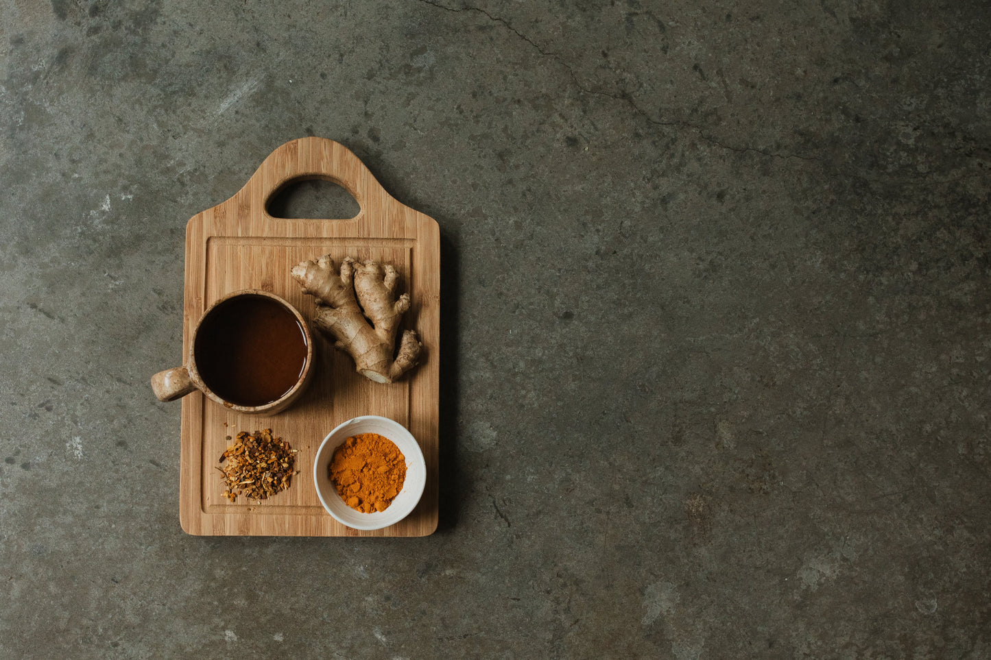Cup of Woodroot Spiced Tea next to anti-inflammatory ingredients turmeric and ginger.