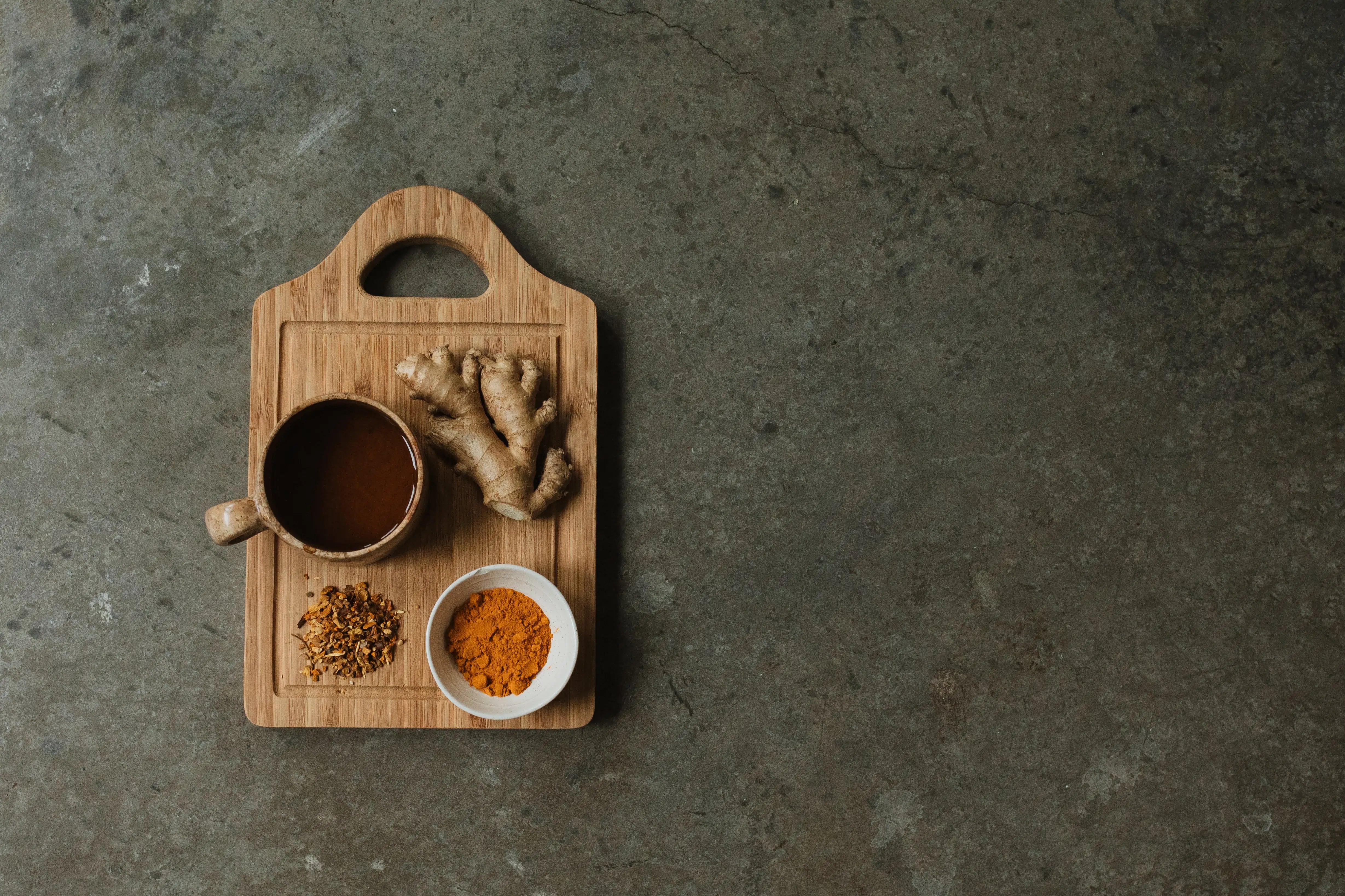 Brewed Woodroot Spiced Tea next to key ingredients ginger and turmeric.