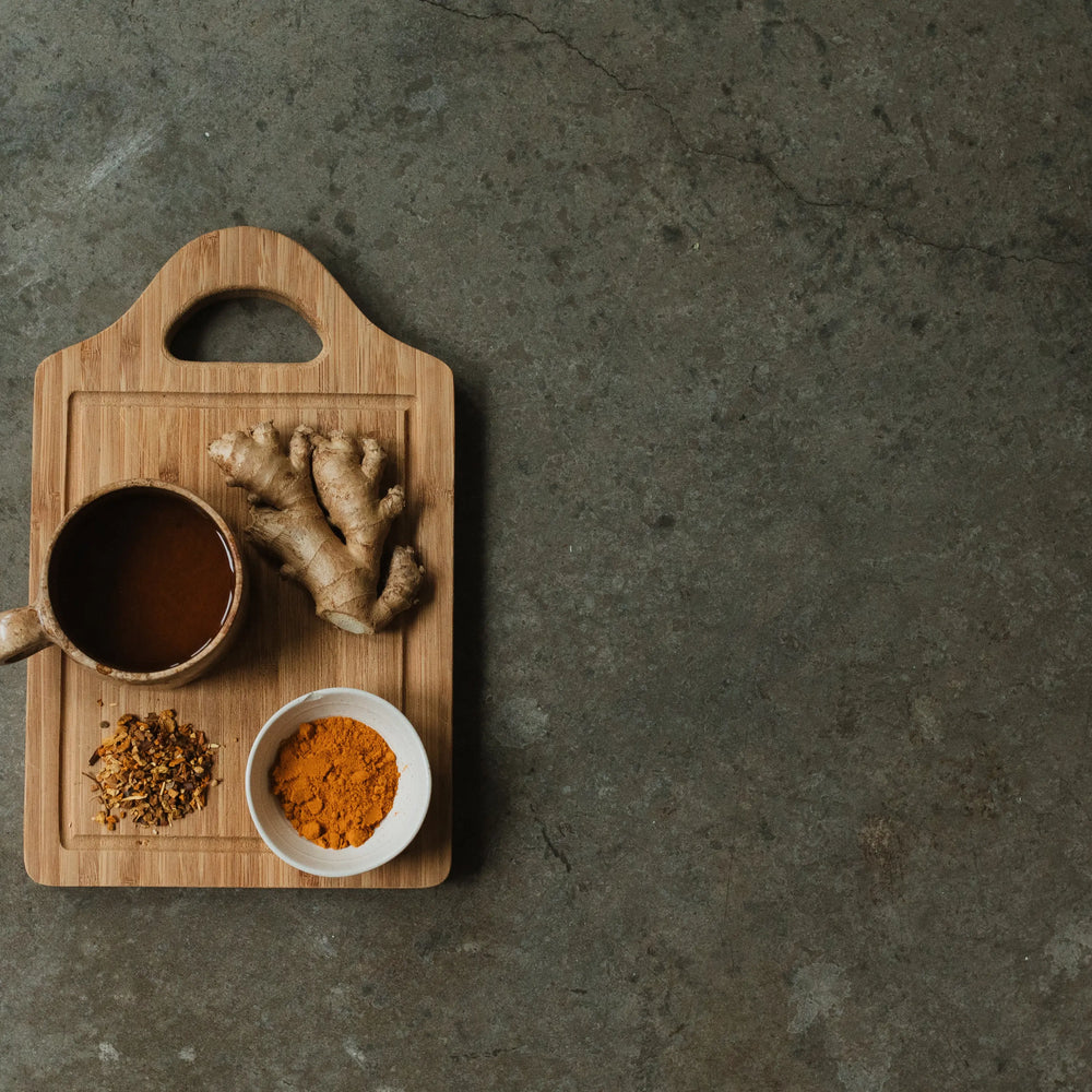 
                  
                    Brewed Woodroot Spiced Tea next to key ingredients ginger and turmeric.
                  
                