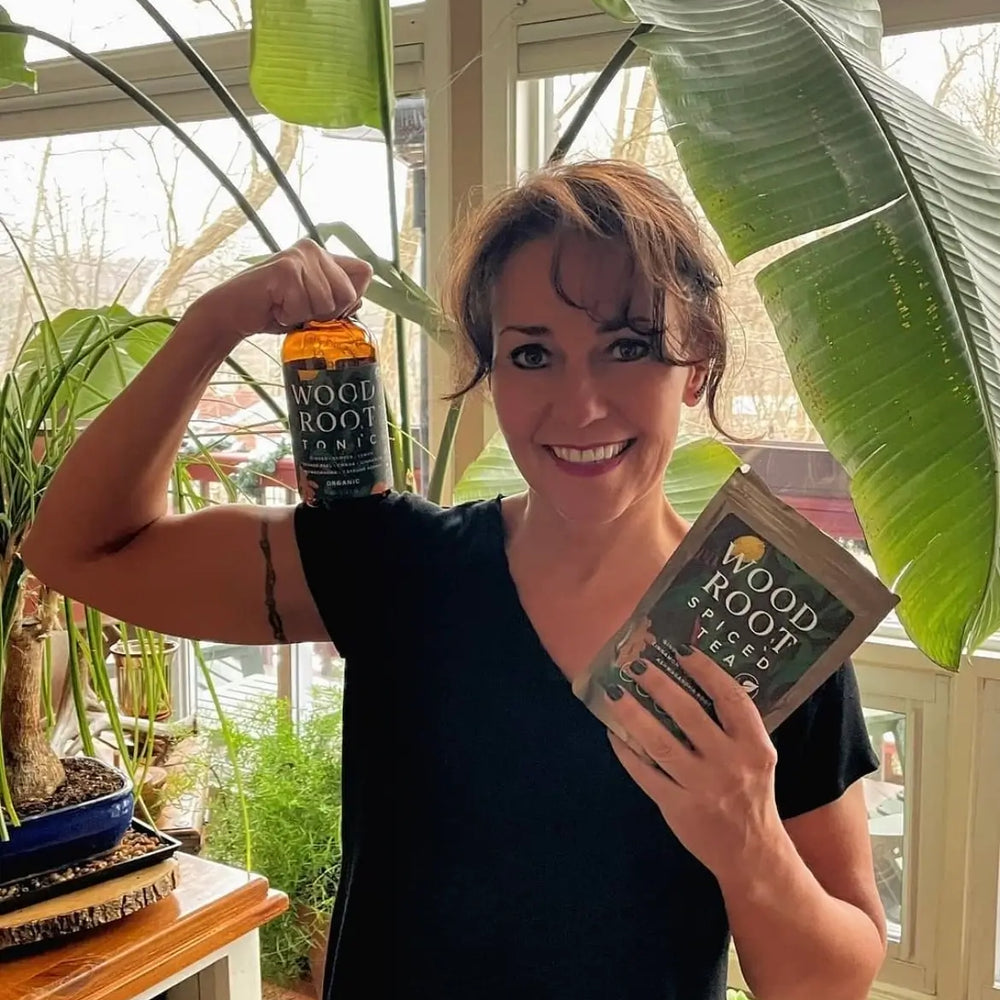 Founder of Morningside Naturals, Jennifer Underwood, holding bottle of Woodroot Tonic and packet of Woodroot Spiced Tea.