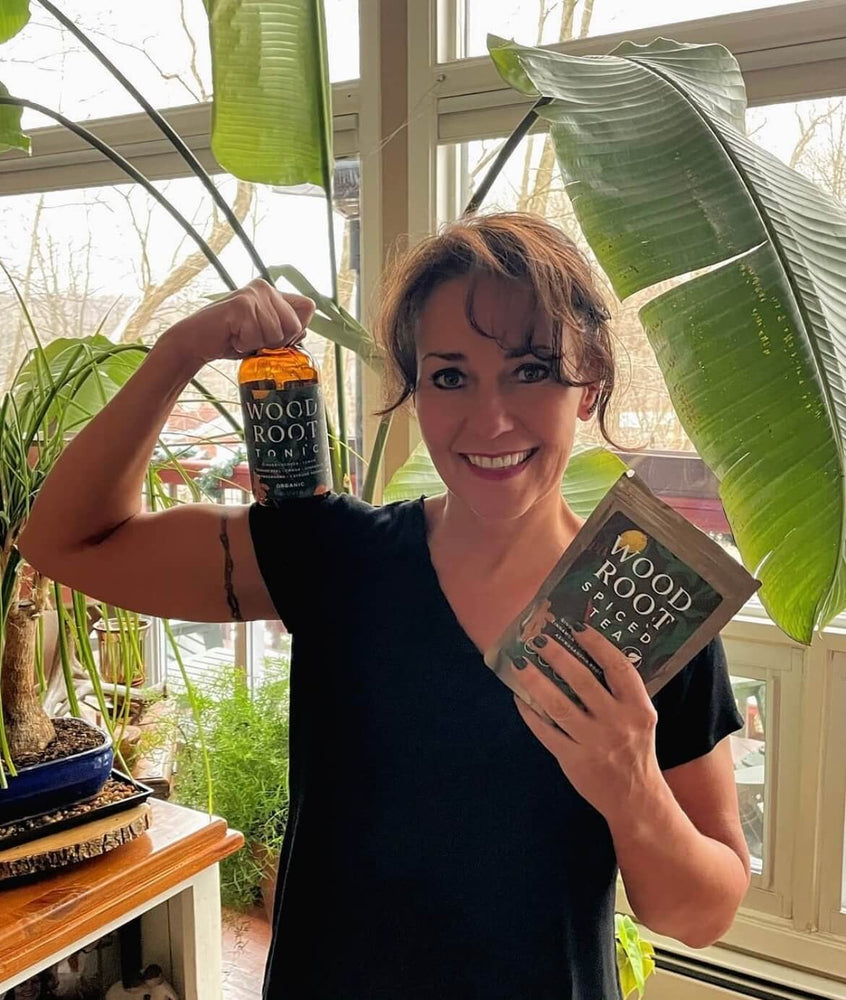 Founder of Morningside Naturals, Jennifer Underwood, holding bottle of Woodroot Tonic and packet of Woodroot Spiced Tea.