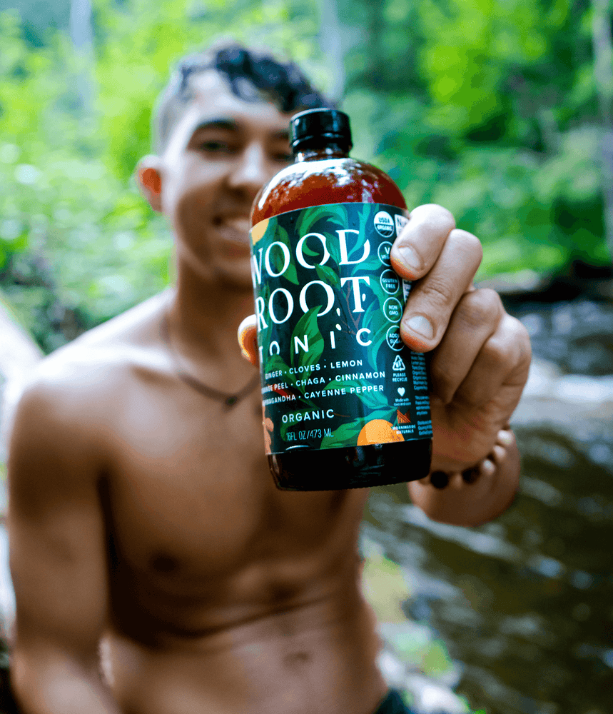 Shirtless man holding a bottle of Woodroot tonic.
