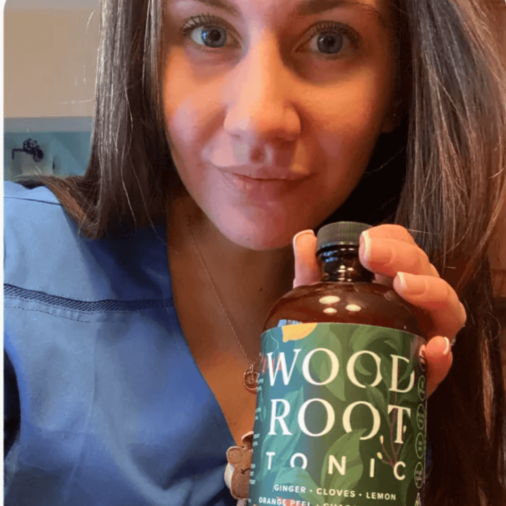 Nurse holding a bottle of Woodroot Tonic, a dietary supplement for gut and immune health.