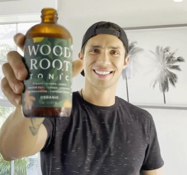 Smiling man holding herbal Woodroot Tonic gut shot. 