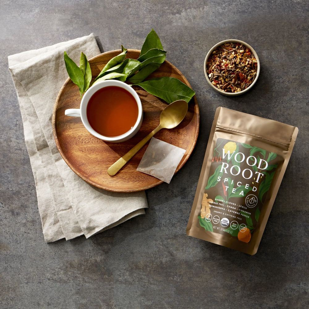 
                  
                    Woodroot Spiced Tea bag next to brewed cup of tea with lose leaf tea in a bowl.
                  
                