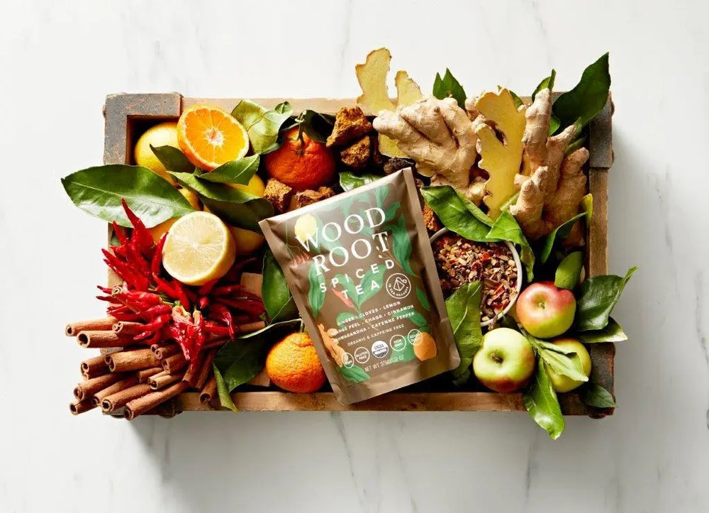 Woodroot Spiced Tea bag on top of wooden cutting board of the tea's ingredients. 