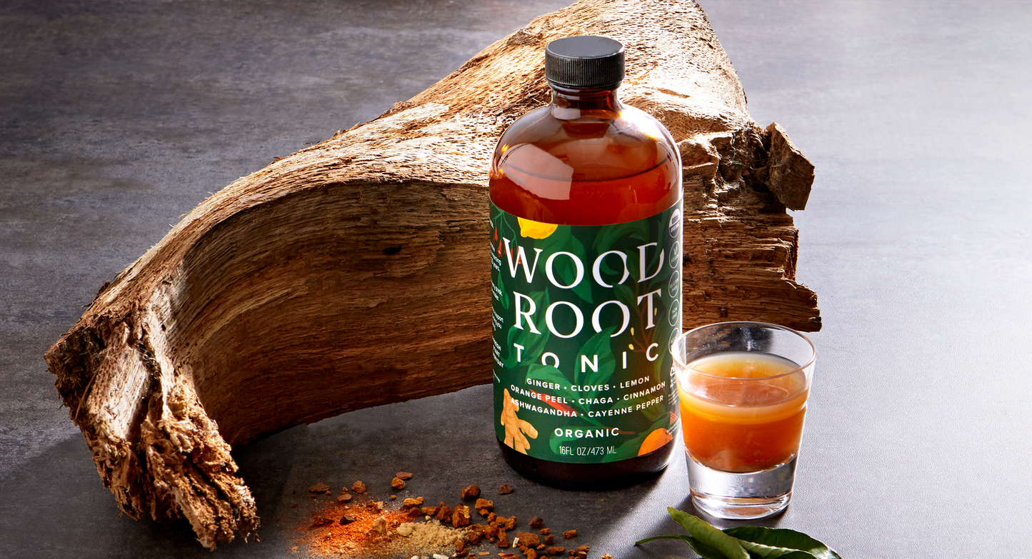 Woodroot Tonic bottle beside a shot glass on a rustic surface, part of a daily regimen for gut health and inflammation reduction.