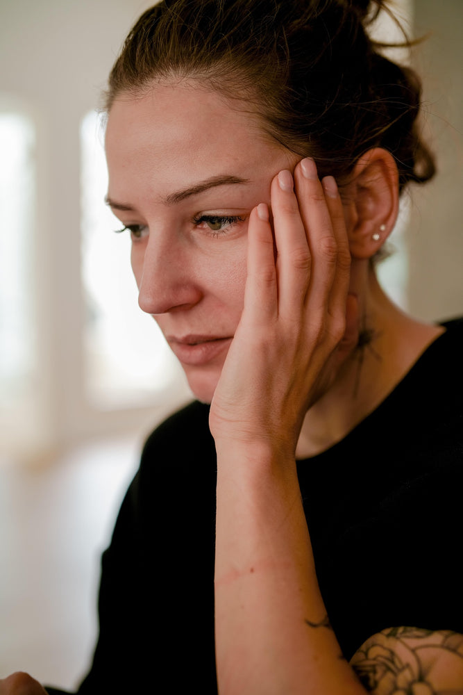 woman with hands next to her temple experiencing anxiety and stress.