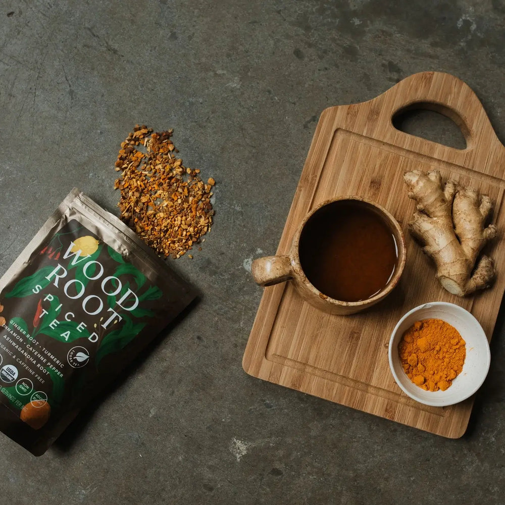 
                      
                        Woodroot Spiced Tea with loose leaf tea out of the bag next to brewed cup of tea and key ingredients. 
                      
                    
