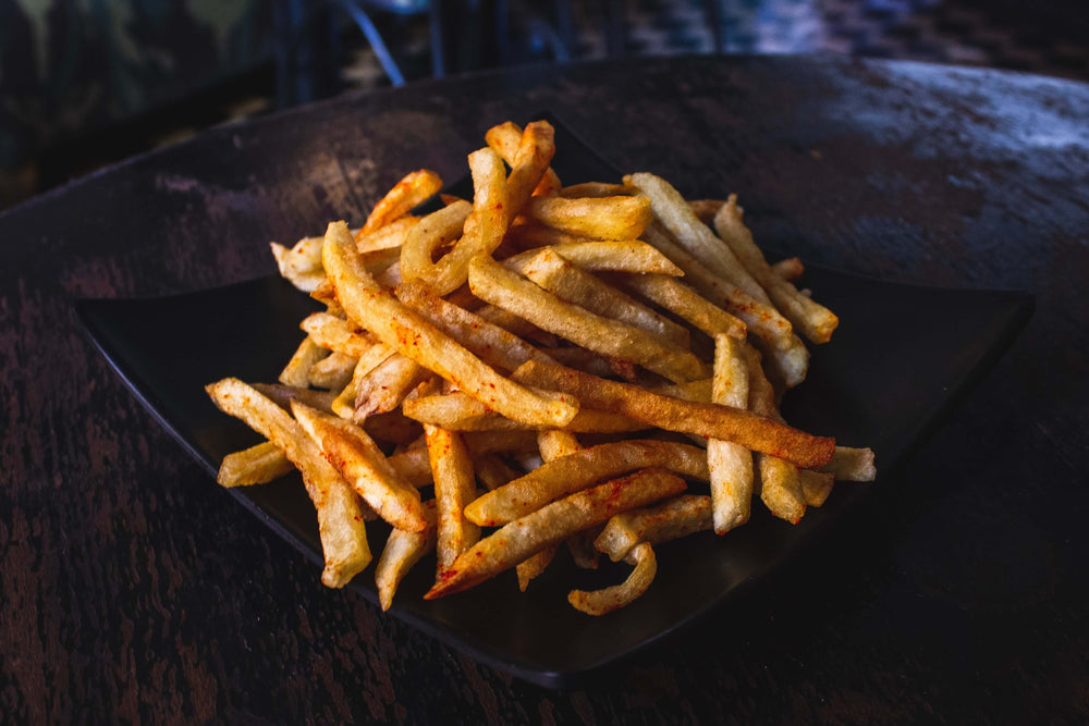 Golden french fries on a dark plate, symbolizing common inflammatory fried foods, with a note on the benefits of dietary changes for health.